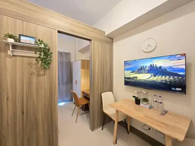 a room with a table and a tv on the wall at 1BR Condotel with Balcony at FAME Residences #FM48 in Manila