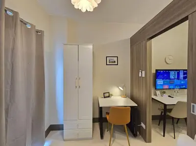 a room with a desk and a white cabinet and a table at 1BR Condotel with Balcony at FAME Residences #FM50 in Manila