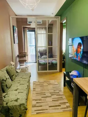 a living room with a couch and a flat screen tv at SPRING RESIDENCES - 2BR Condo near Airport with balcony and pool views in Manila