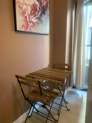 a table and a bench in a room with a painting at SPRING RESIDENCES - 2BR Condo near Airport with balcony and pool views in Manila