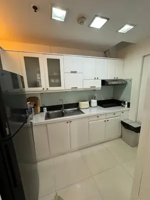 a kitchen with white cabinets and a sink and a refrigerator at Minimalist Luxury Spacious 1 Bedroom in Burgos Circle in Manila
