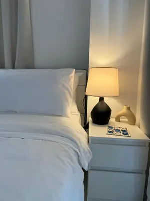 a bedroom with a bed with a lamp on a night stand at Minimalist Luxury Spacious 1 Bedroom in Burgos Circle in Manila
