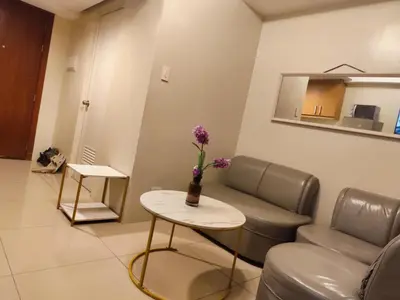 a waiting room with a couch and a table with flowers at Angelica Staycation at Mall of Asia Shell Residence in Manila