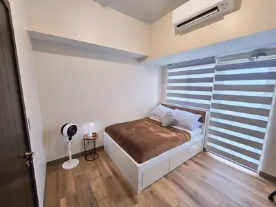 a bedroom with a bed and a window with a fan at Pet & WFH Friendly Home Near BGC in Manila