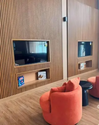 a living room with an orange chair and a tv at Pet & WFH Friendly Home Near BGC in Manila