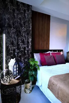 a bedroom with a large bed with red and purple pillows at Budget Suite Paranaque in Manila
