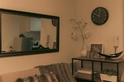 a mirror in a living room with a couch and a clock at The Skyline Oasis Makati in Manila
