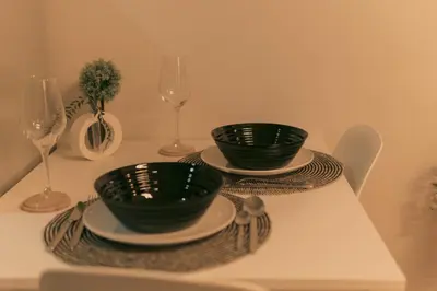 two green bowls and plates on a table with wine glasses at The Skyline Oasis Makati in Manila