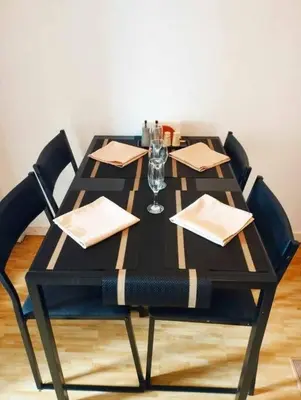 a wooden table with chairs and a black table with glasses at Azure - Stellar Property in Manila