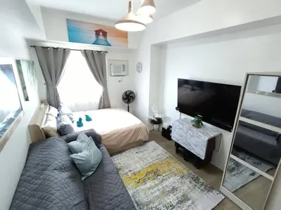 a living room with a bed and a television at University Belt Cozy Studio at Vista Recto-33rd Floor in Manila