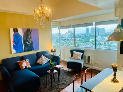 a living room with a blue couch and a large window at Greenhills 1BR Lower Penthouse w Panoramic View in Manila