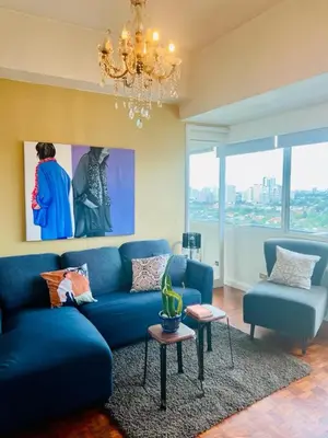 a living room with a blue couch and a chandelier at Greenhills 1BR Lower Penthouse w Panoramic View in Manila
