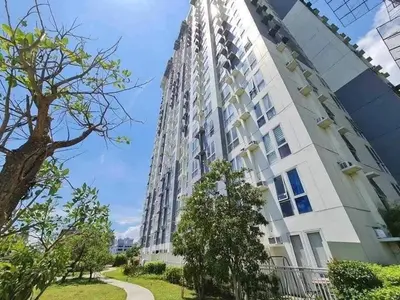 a tall white building with trees in front of it at Chill Spot Staycation in Pasig in Manila