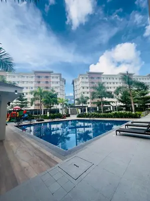 a swimming pool in front of two large buildings at Zenrise Staycation in Trece Martires