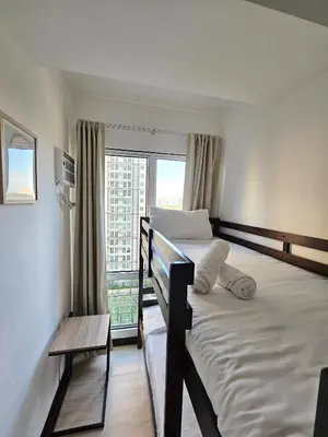 a bedroom with two bunk beds and a window at Spacious 2BR Condo San Lorenzo Place 4KM Airport in Manila