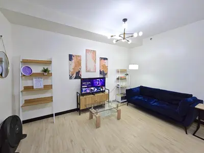 a living room with a blue couch and a tv at Spacious 2BR Condo San Lorenzo Place 4KM Airport in Manila