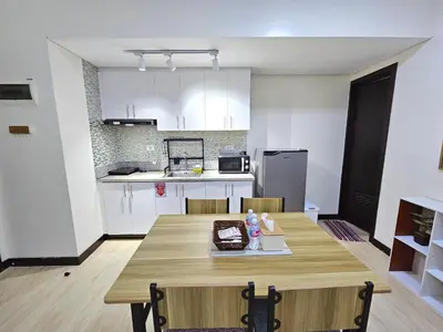 a kitchen and dining room with a wooden table at Spacious 2BR Condo San Lorenzo Place 4KM Airport in Manila