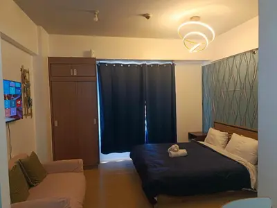 a bedroom with a bed and a couch at Avah cozy condotel 150 Newport boulavevard Pasay city in Manila