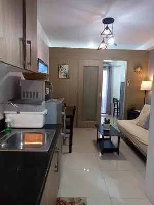 a kitchen with a sink and a living room at Shore Residence Manila Bay City Lights View MOA Complex in Manila
