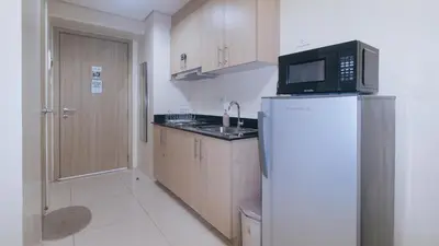 a small kitchen with a refrigerator and a microwave at SMDC Breeze Residences by RedDoorz in Manila