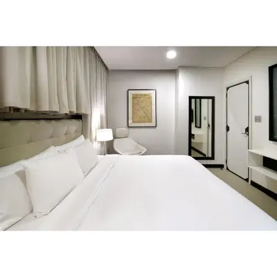 a bedroom with a large white bed and a chair at Summit Hotel Magnolia in Manila
