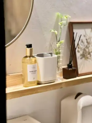 a bathroom shelf with a bottle of soap and a mirror at Modern minimalist house in the heart of Antipolo in Antipolo