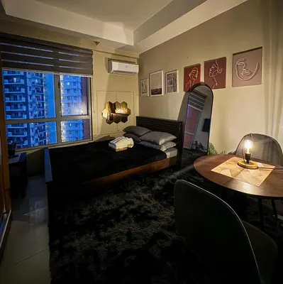 a bedroom with a bed and a table and a window at Sunshine 100 Stylish Condo by The Capital Cabin in Manila