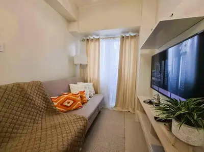a living room with a couch and a flat screen tv at Comfy Condo Near NAIA Airport in Manila