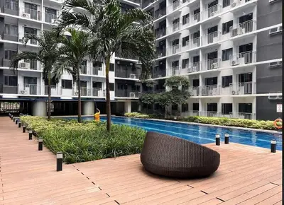 a wicker chair sitting on a wooden deck in front of a building at Cozy and aesthetic unit near MOA Airport and IKEA in Manila