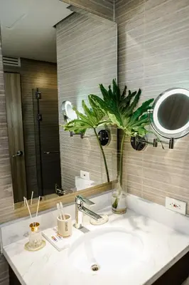 a bathroom with a sink with a mirror and a plant at Luxe Suite at BCCT - BGC's Prime Studio - Gym, Infinity Pool with breathtaking skyline view in Manila