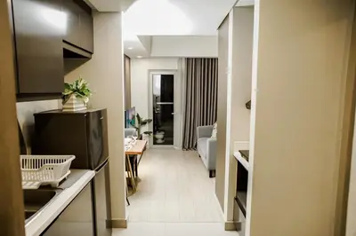 a hallway of a living room with a television and a living room at Luxe Suite at BCCT - BGC's Prime Studio - Gym, Infinity Pool with breathtaking skyline view in Manila