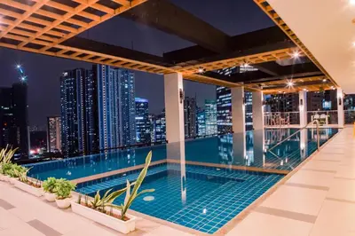 a swimming pool on the roof of a building with a city skyline at Luxe Suite at BCCT - BGC's Prime Studio - Gym, Infinity Pool with breathtaking skyline view in Manila