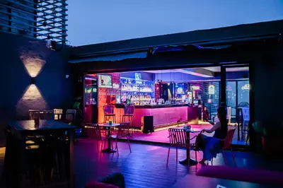 a woman sitting at a bar at night at Luxe Suite at BCCT - BGC's Prime Studio - Gym, Infinity Pool with breathtaking skyline view in Manila