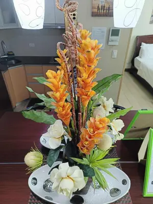 a vase filled with orange flowers on a table at Two Palmtree Villas cluster3 rooms across NAIA terminal 3 in Manila