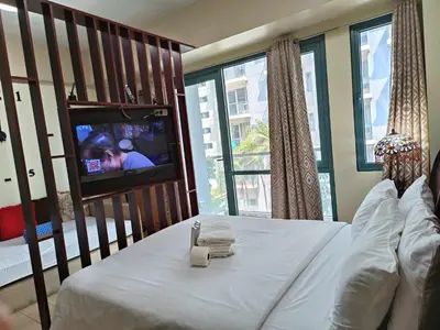 a bedroom with a bed and a tv in a room at Two Palmtree Villas cluster3 rooms across NAIA terminal 3 in Manila