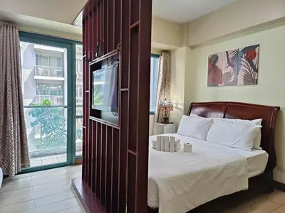 a bedroom with a bed with a tv and a window at Two Palmtree Villas cluster3 rooms across NAIA terminal 3 in Manila