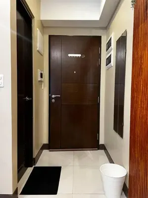 a bathroom with a wooden door and a toilet at Cozy space in Viceroy Residences McKinley Hill Taguig in Manila