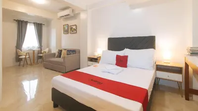 a hotel room with a bed and a chair at RedDoorz at Delorian Residences in Manila