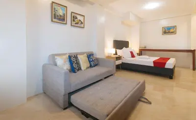 a living room with a couch and a bed at RedDoorz at Delorian Residences in Manila