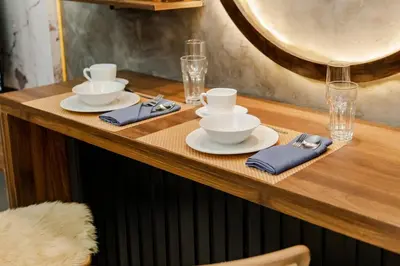 a wooden table with plates and bowls and glasses at 1BR Makati, Lush Residences M004 in Manila