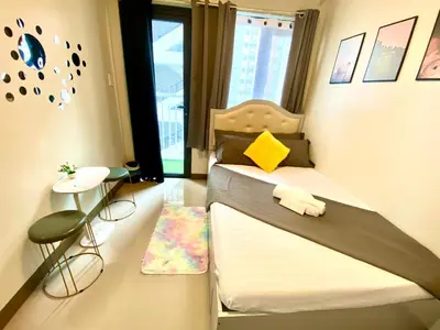 a small bedroom with a bed and a small table at Cozy Blossom near NAIA in Manila