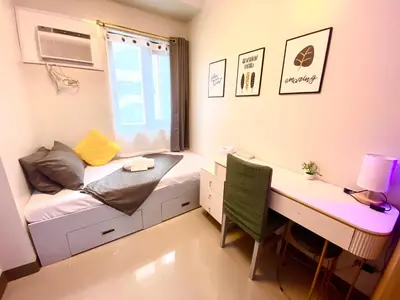 a small room with a desk and a bed and a window at Cozy Blossom near NAIA in Manila