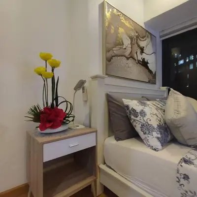 a bedroom with a bed and a table with flowers on it at Spacious 1BR Milano by Versace in Makati in Manila