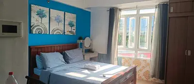 a bedroom with a bed with blue walls and a window at cozy Avah condotel newport in Manila