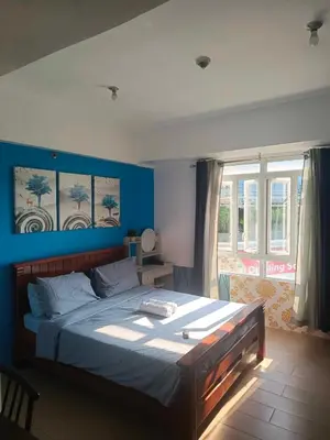 a bedroom with a large bed with blue walls at cozy Avah condotel newport in Manila