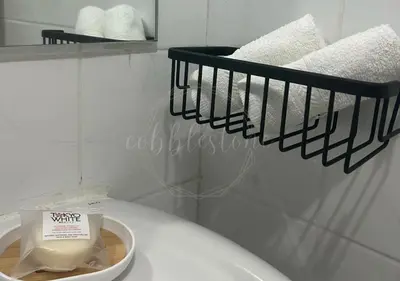 a bathroom with a white toilet and a rack of towels at Cobblestone City Stays - SM Mezza 1 Residences in Manila
