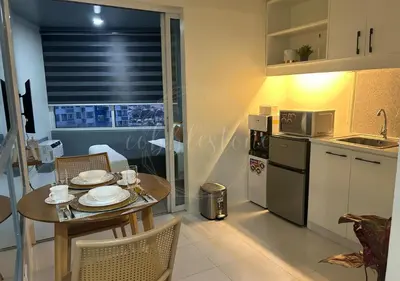 a kitchen with a table and a kitchen with a microwave at Cobblestone City Stays - SM Mezza 1 Residences in Manila