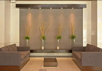 a lobby with two brown couches and plants at Cobblestone City Stays - SM Mezza 1 Residences in Manila