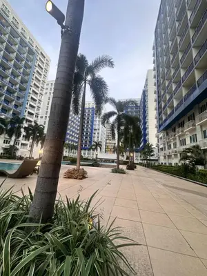 a sidewalk with palm trees in a city with tall buildings at 2bedroom unit at Sea Residences infront of MOA Arena, SMX & Ikea in Manila