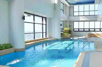 a large swimming pool with blue water in a building at Modern 1BD in Ortigas, WiFi ,Netflix ,Pool ,Gym in Manila